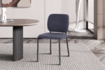 Een moderne eetkamer met PROMO - Stoel 'Sophia' Stof Donkergrijs stoelen op slanke metalen poten naast een ronde tafel. De ruimte is voorzien van marmeren vloeren, een vloerkleed met structuur en een neutrale inrichting. (Set van 2 stoelen per doos).