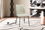 De Stoel 'Lara' Stof Ote Sea 140 Ecru stoelen (set van 2) staan op een wit vloerkleed met zwarte lijnen, naast een tafel met marmeren blad en geometrisch zwart decor, en geven de kamer een moderne stijl.