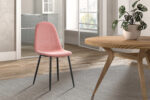 Een moderne eetkamer heeft een ronde houten tafel, een Stoel 'Boy' Fluweel Roze stoel met zwarte metalen poten, een potplant op tafel en grote ramen die de ruimte overspoelen met natuurlijk licht.