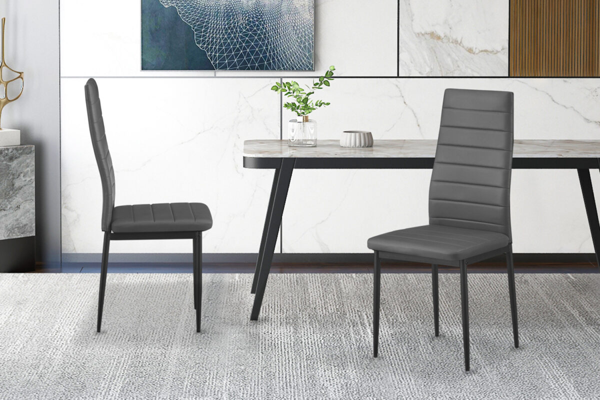 Vier moderne grijze Cato/Kenzo PU-stoelen staan op een lichtgrijs tapijt rond een eettafel met marmeren blad, met abstracte kunst op de decoratieve muur en een plantje op tafel.