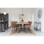 Een moderne eetkamer heeft een houten tafel, zes Harbo Dining Chairs in vintage bruin PU met zwarte poten, een hanglamp erboven, een keukengedeelte met twee zwarte barkrukken, plus een decoratieve kar en muurkunst aan de rechterkant.