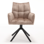 De Eetkamerstoel Dani Velvet Beige is een moderne, met beige fluweel beklede fauteuil met een gecapitonneerde, getufte zitting en rugleuning, schuine armleuningen en vier schuin geplaatste, zwart metalen poten tegen een effen witte achtergrond.