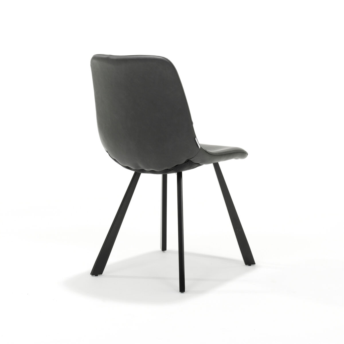 Een moderne stoel met een strakke zwarte zitting en rugleuning, en slanke, schuin aflopende zwarte metalen poten. De stoel staat op een effen witte achtergrond, wat het minimalistische design en de gladde afwerking benadrukt.