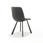Een moderne stoel met een strakke zwarte zitting en rugleuning, en slanke, schuin aflopende zwarte metalen poten. De stoel staat op een effen witte achtergrond, wat het minimalistische design en de gladde afwerking benadrukt.