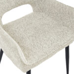 Close-up van de Eetkamerstoel Ray - Beige, een moderne stoel met lichtbeige stoffen bekleding, een gebogen rugleuning met uitsparing en zwarte schuine poten.
