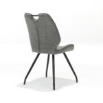 De Stoel Hardy zwart Stof Soft Steel is een moderne grijze stoel met een gecapitonneerde rugleuning, zwarte metalen poten en een kleine greepuitsparing bovenaan, afgebeeld op een witte achtergrond.