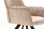 Close-up van de Eetkamerstoel Nova Beige, een modern gestoffeerde fauteuil met een zachte, fluweelachtige textuur, gecapitonneerde armleuningen en een zwarte schuine draaivoet. Afgebeeld tegen een effen witte achtergrond.