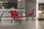 Een moderne eethoek met twee Stoel 'Lizzy' Stof Ote Share 230 Rood stoelen, een strakke tafel met gebogen poten, grijze kasten, decoratieve planken op de achtergrond, glanzende grijze tegelvloer en een deel van een bank aan de rechterkant.