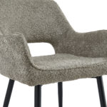 Een close-up van de Eetkamerstoel Ray - Taupe, met gestructureerde taupe bekleding, gebogen armleuningen en slanke zwart metalen poten.