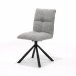 De Leon stoel MT2-Stof Alpine Steel #149 heeft een moderne zitting en rugleuning met kussens en vierkant tuftwerk in lichtgrijze bekleding, ondersteund door vier schuine zwart metalen poten en een 180-graden draaivoet.