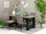 Moderne eetkamer met een rechthoekige houten tafel, vijf Stoel Hardy zwart Stof Soft Antraciet stoelen, decoratieve vazen, kaarsen, hanglampen, een groot bloemstuk en verschillende groene planten op een vloerkleed met patroon.