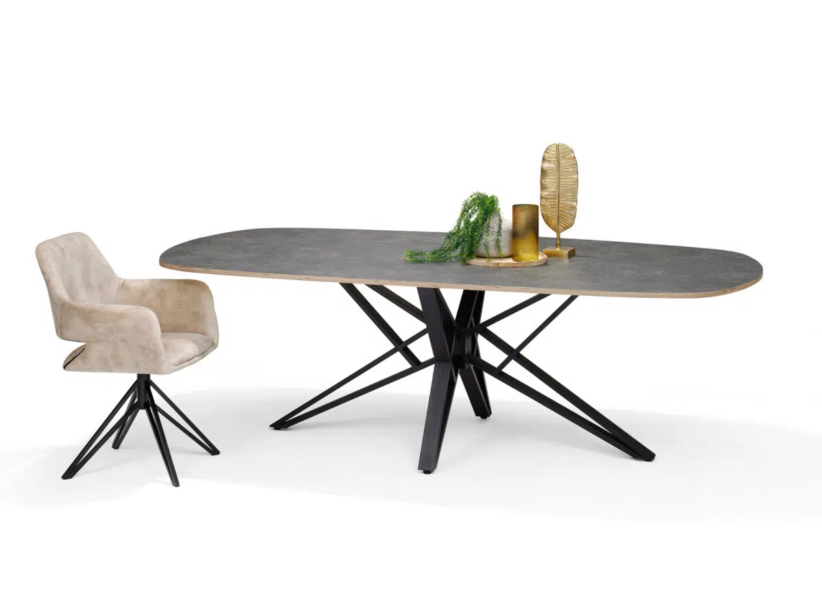Een moderne eetkamerset met een grijze ovale tafel met een houten rand en zwarte, kruisende poten. Bij de tafel staat een beige gestoffeerde stoel met draaivoet. Op de tafel staan gouden en groene decoraties.