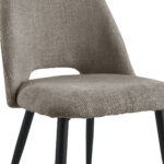 Een close-up van de Eetkamerstoel Monta - Taupe toont de beige stoffen zitting en rugleuning, slanke zwarte metalen poten en een kleine uitsparing in de onderrug.
