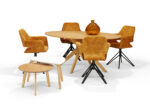 Een moderne eetset met een ronde houten tafel, vijf Katy Eetkamerstoel - Aurora Velours Antraciet draaivoetstoelen, twee in elkaar geschoven bijzettafeltjes en een amberkleurige glazen vaas op tafel, alles tegen een witte achtergrond.