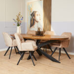 Een moderne eetkamer met een houten ovale tafel, vijf Eetkamerstoel Nova stoelen in beige met zwarte poten, een vaas met bloemen, glazen flessen en een portret van een vrouw met een gevederd hoofddeksel aan de muur.