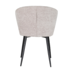 De Eetkamerstoel Pete - Stof Beige is een moderne stoel met lichtbeige bekleding, een gebogen rugleuning en vier slanke zwarte metalen poten, van achteren gezien tegen een witte achtergrond.