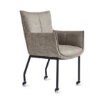 De Eetkamerstoel Thomas - Microleder Taupe is een moderne fauteuil met taupe microlederen bekleding, zwarte metalen poten en vier zwenkwielen, tegen een witte achtergrond.