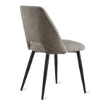 De Eetkamerstoel Monta - Taupe is een moderne stoel met een gestructureerde taupe beklede zitting en rugleuning, vier slanke schuine zwarte metalen poten, van achteren gezien tegen een witte achtergrond.