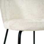 Een close-up van Eetkamerstoel Lio - Beige, met lichtbeige bekleding en zwarte metalen poten, tegen een witte achtergrond.