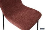 Close-up van de Eetkamerstoel 'Alice' Bouclé Roze, met de roze bouclé stoffen zitting en slanke zwarte metalen poten. De afbeelding benadrukt de stoffering en materiaaldetails. (Set van 2 stoelen per doos).