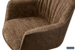 Close-up van de Stoel 'Lucie' Bouclé Zand Rug PU Bruin fauteuil, met een zandkleurige bouclé gestructureerde zitting en rugleuning, en gladde bruine kunstleren zijkanten en rugleuning. Het Roussbeau-logo is zichtbaar in de rechterbenedenhoek.