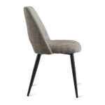 De Eetkamerstoel Monta - Taupe is een moderne stoel met een beige gestoffeerde zitting en rugleuning, slanke zwarte metalen poten, afgebeeld in zijaanzicht tegen een witte achtergrond.