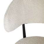 Close-up van de Eetkamerstoel Sander - Teddy Crème, met een moderne gebogen rugleuning en zitting bekleed met zachte gebroken witte teddy stof, met slanke zwarte metalen steun die de rugleuning en zitting verbindt.
