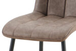 Een close-up van de Set van 4 stoelen 'Furas' Vintage PU Bruin (1c) toont de gecapitonneerde zitting met bruine getufte bekleding en zwarte metalen poten, waarbij de textuur en stikseldetails benadrukt worden.