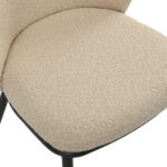 Close-up van de Eetkamerstoel Loa - Bouclé Taupe stoel, met een zitting van beige bouclé stof met een gebogen rugleuning en gedeeltelijk zichtbare zwarte metalen poten.