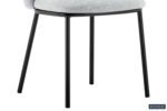 Een close-up van de Stoel 'Arthur' Stof Ote Belfast 41 Lichtgrijs toont de lichtgrijze beklede zitting en slanke zwarte metalen poten, met de nadruk op het onderste gedeelte. Het Rousseau-logo is zichtbaar in de rechterbenedenhoek.