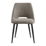 De Eetkamerstoel Monta - Taupe is een moderne eetkamerstoel met een gestructureerde taupe bekleding, een gebogen rugleuning met een kleine uitsparing en vier slanke zwarte metalen poten, tegen een witte achtergrond.