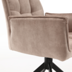 Een close-up van de Eetkamerstoel Dani Velvet Beige, een moderne fluweelbeige stoel met armleuningen en een zwart metalen draaivoet, tegen een witte achtergrond.