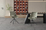 Twee groene eetkamerstoelen met een moderne tafel in een interieur met een neutrale kleurstelling.