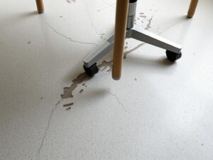 Beschadigde PVC vloer door harde stoelwieltjes met zichtbare krassen en slijtage