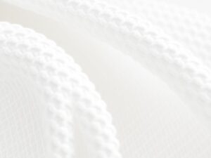 Close-up van witte boucle stof met kenmerkende lussen en textuur in een neutrale setting.