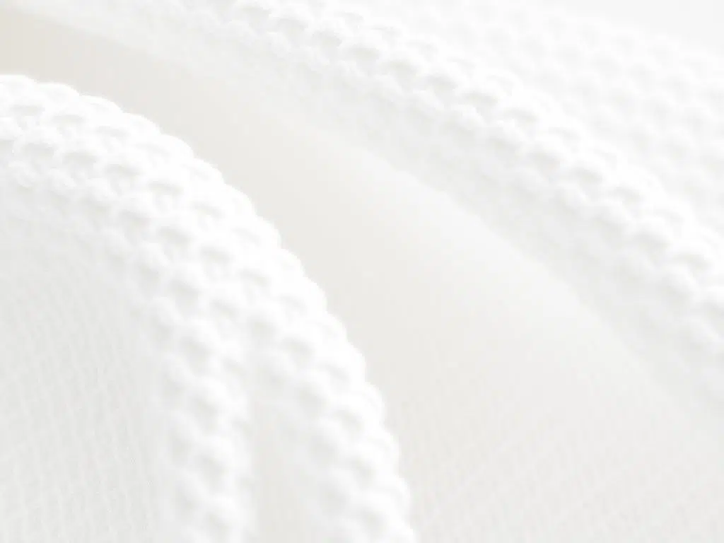 Close-up van witte boucle stof met kenmerkende lussen en textuur in een neutrale setting.