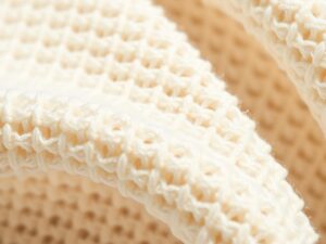 Close-up van beige boucle stof met zichtbare lusjes en textuur in een neutrale setting.