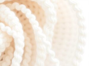 Close-up van een witte boucle stof met karakteristieke lussen en krullen in een textuur.