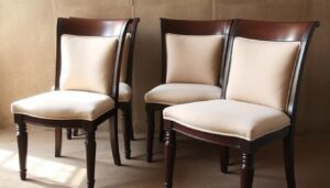 Set van vier tweedehands eetkamerstoelen met houten frames en beige kussens.