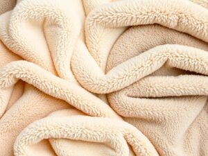 Teddy stof in verschillende kleuren, met een zachte en pluizige textuur, uitgestald op een vlakke ondergrond.