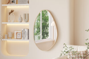 Een moderne, minimalistische woonkamer heeft ingebouwde planken met decoratieve vazen, de 'Rana' 80x50 Oude eik spiegel die een raam met groen weerspiegelt, een sofa met een kussen met patroon en een bladplant in de buurt.