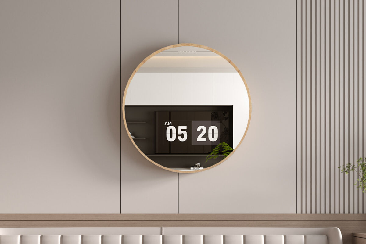 De Spiegel 'Roxy' 80x80 Oude eik (1c), een ronde spiegel met een lichte houten lijst, hangt aan een beige muur die een digitale klok van 5:20 AM, moderne kasten en een groene plant weerspiegelt. De minimalistische kamer heeft subtiele verticale lijnen.