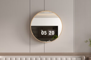 De Spiegel 'Roxy' 80x80 Oude eik (1c), een ronde spiegel met een lichte houten lijst, hangt aan een beige muur die een digitale klok van 5:20 AM, moderne kasten en een groene plant weerspiegelt. De minimalistische kamer heeft subtiele verticale lijnen.