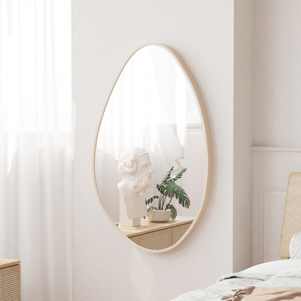 In een knusse slaapkamerhoek hangt de 'Romi' 80x50 Oude eik wandspiegel met een wit borstbeeld en een potplant, bij een raam met transparante gordijnen, een draaiplateau en een keurig opgemaakt bed.