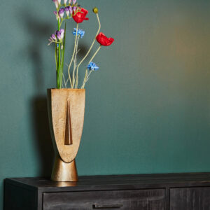 De Vaas Fin - Antiek goud | Large, gevuld met rode, paarse en blauwe kunstbloemen, staat op een donkere houten kast tegen een effen groene muur.