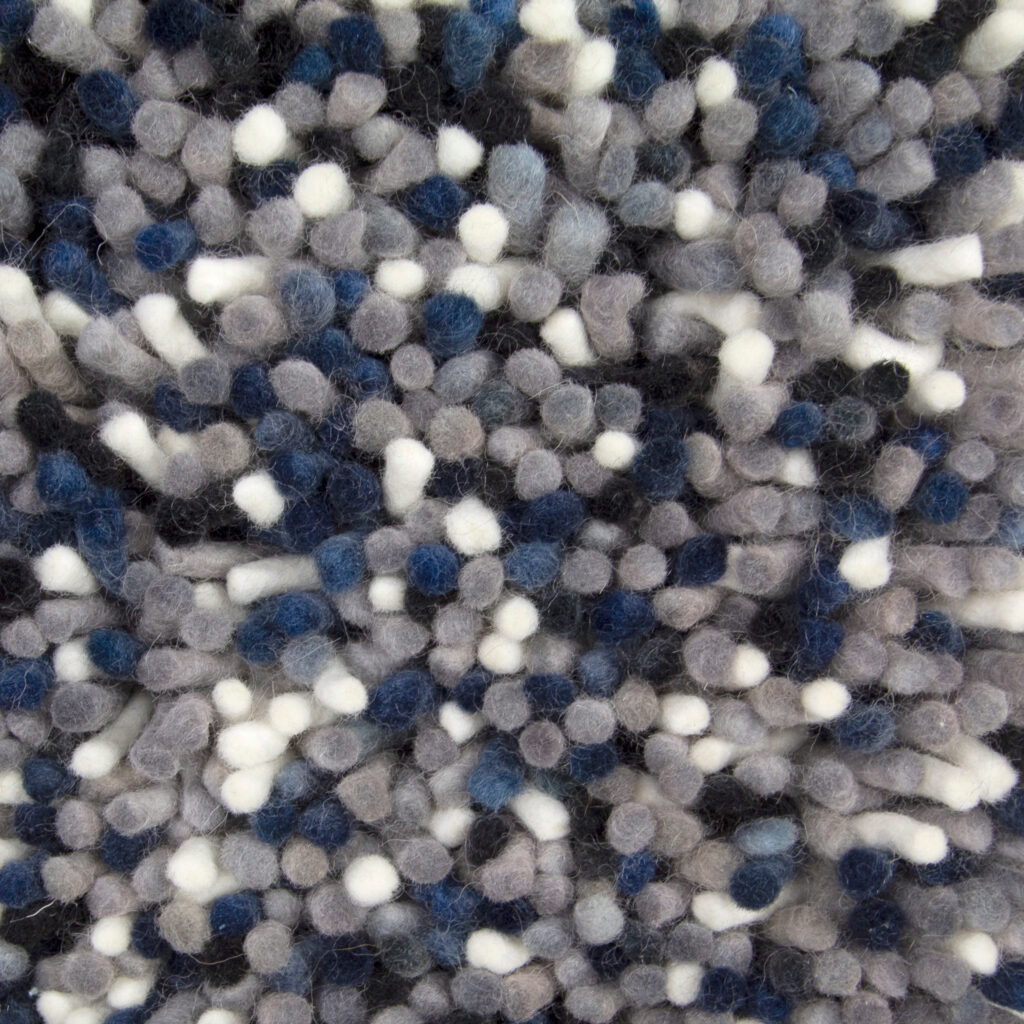 Close-up van het Alto Indigo 250 170x230 tapijt, met dikke vezels in lussen in grijze, blauwe, witte en zwarte tinten voor een zachte, geclusterde, wollige textuur.