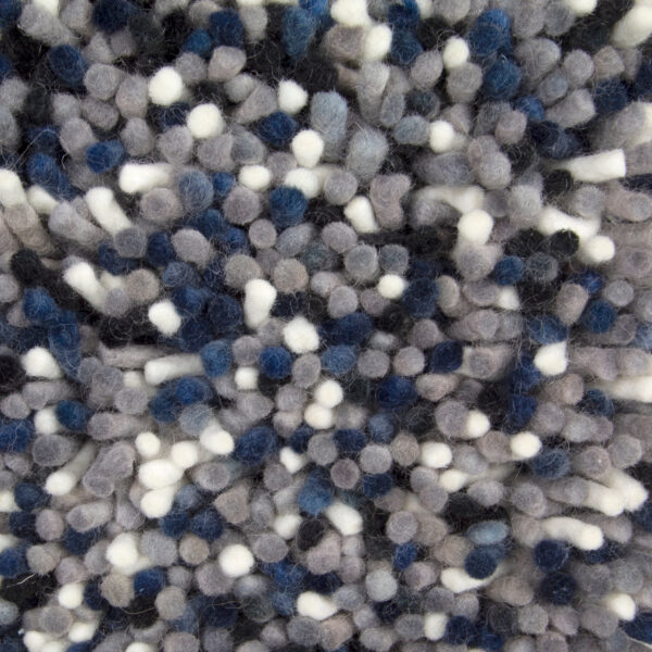 Close-up van het Alto Indigo 250 200x300 tapijt met dicht opeengepakte, zachte, ronde plukjes in grijze, blauwe, zwarte en witte tinten die een gespikkelde, gestructureerde driedimensionale look creëren.