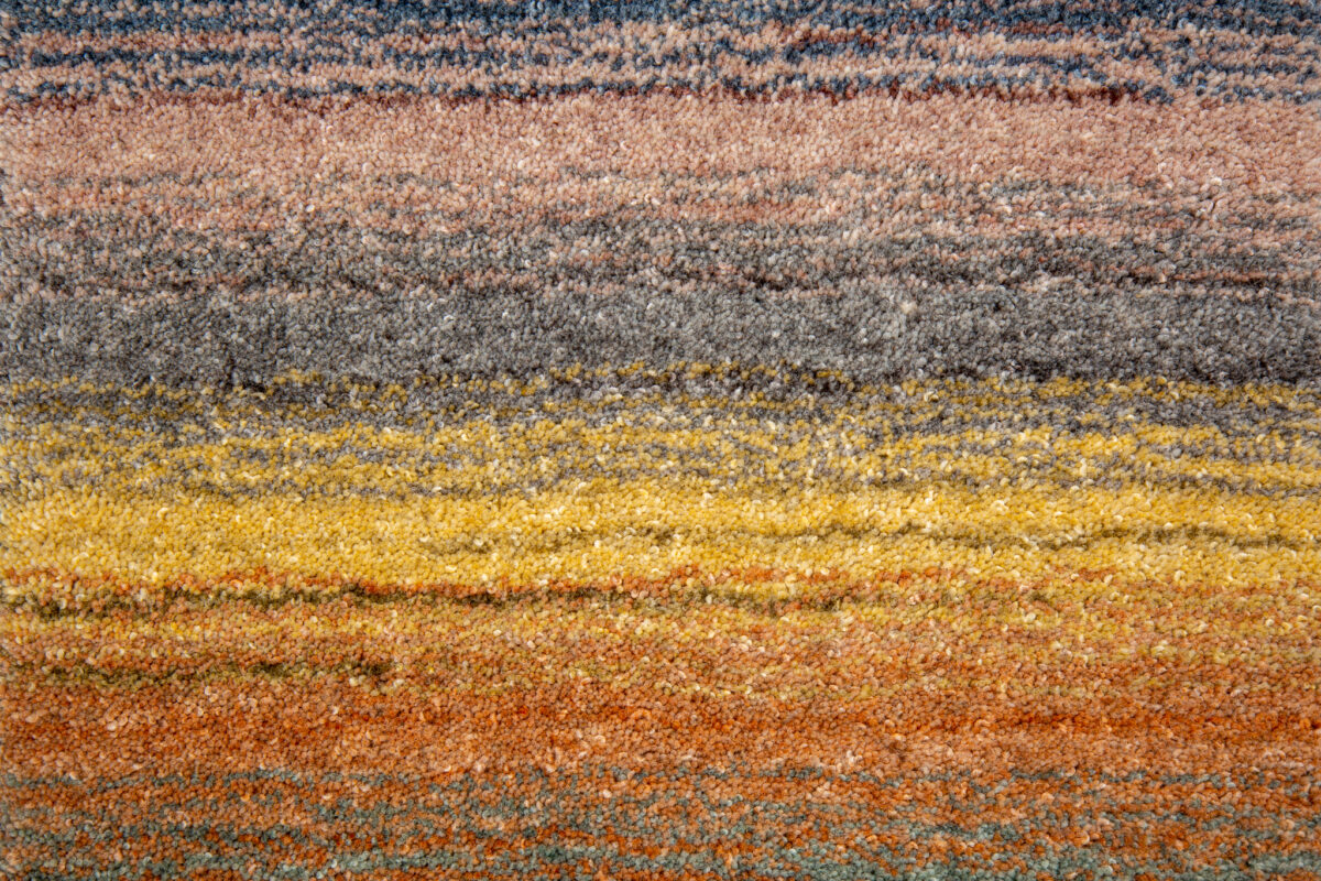 Het Portofino Multi 04 170x230 tapijt heeft een gestructureerd oppervlak met horizontale strepen in blauwe, grijze, oranje en gele tinten die een opvallend verlooppatroon creëren.