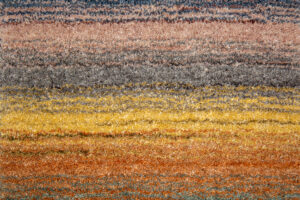 Het Portofino Multi 04 170x230 tapijt heeft een gestructureerd oppervlak met horizontale strepen in blauwe, grijze, oranje en gele tinten die een opvallend verlooppatroon creëren.