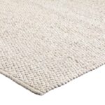 Close-up van de hoek van het tapijt Donna Cloud White 815 200x300 met een grof, kiezelachtig oppervlak in gebroken wit.